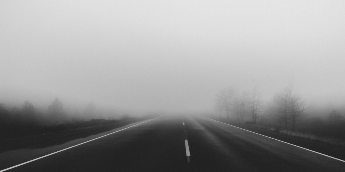 black and white photo of highway in fog